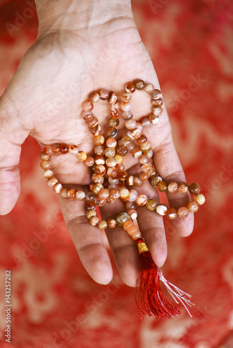 Mala of Buddhist prayer in red and white semi-precious stone and hand offering photo