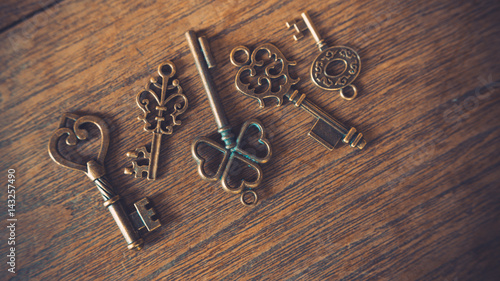 Antique skeleton padlock and retro lock keys on wooden texture background.