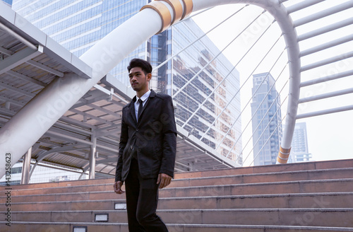 Confident businessman going down and walking on stairs