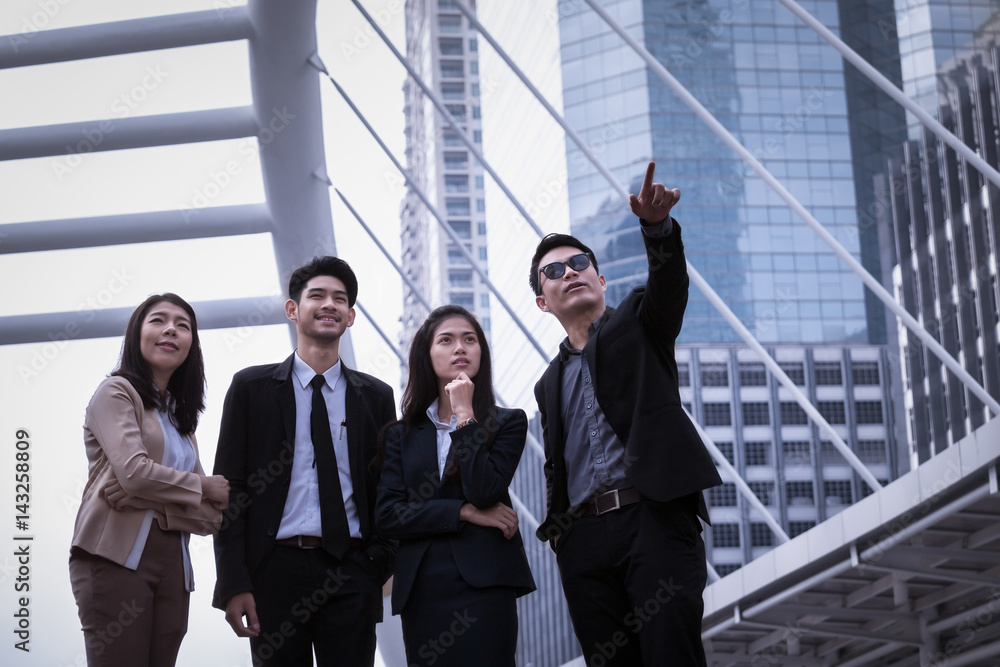 Asian business man and woman group standing on ground and to point the finger away and business city modern office building background. Asian business man and woman group standing on ground and to point the finger away and business city modern office building background.