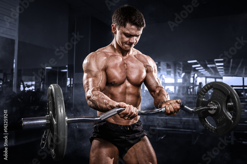 Athlete muscular bodybuilder in the gym training with bar