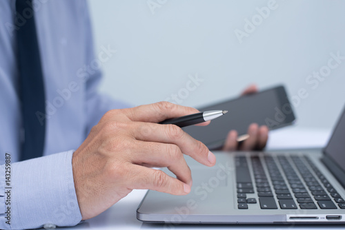 Businessman holding pen and using tablet computer