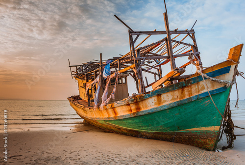 Old boat in the rays of a bright sun at sunset  orange  sky