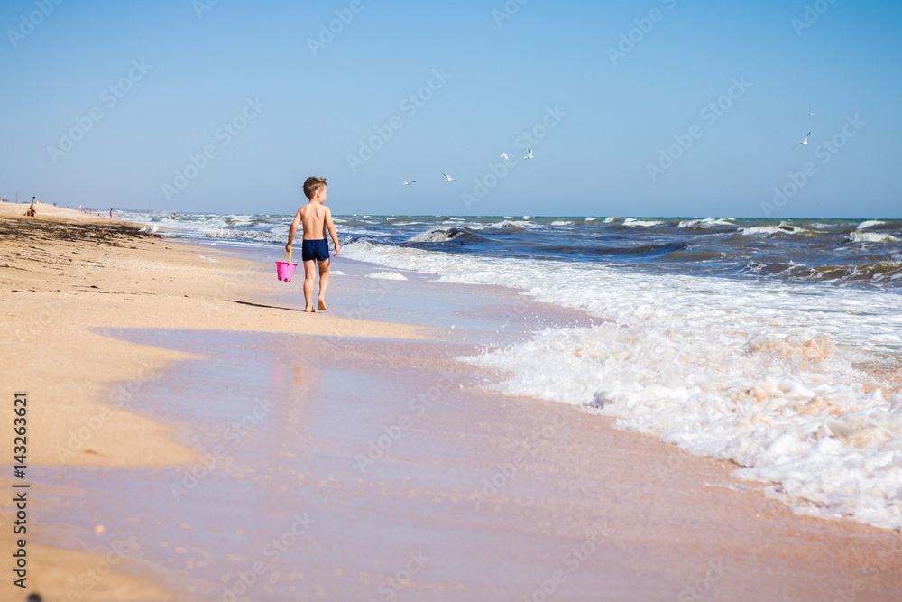 The boy walks along the coast