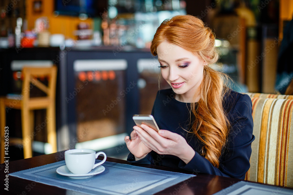Image of young female reading sms on the phone in cafe Image of young female reading sms on the phone in cafe