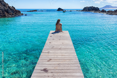 Spain, Canary Islands, Fuerteventura, Isla de lobos. Topless girl on a pier clear transparent water photo