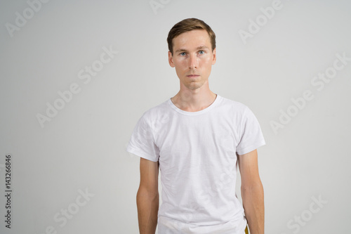 Man in sportswear standing in a white room, half-length portrait. © Vasily Merkushev