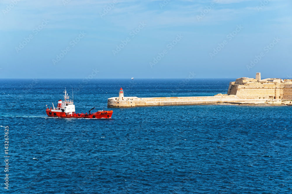 Fototapeta premium Dry cargo carrier and Breakwater at Fort Ricasoli of Kalkara