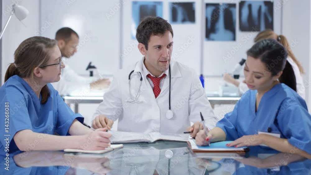 Medical team in a meeting. Hands holding tablet in foreground with brain scan Medical team in a meeting. Hands holding tablet in foreground with brain scan
