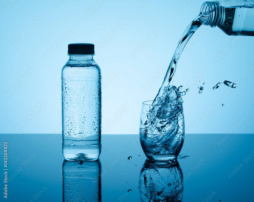 Bottle with creative splashing water in the glass Bottle with creative splashing water in the glass