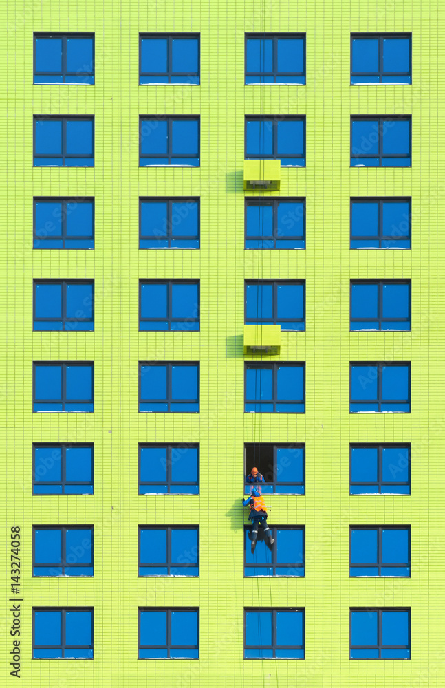 Workers install air conditioners on the wall of a newly built residential building Workers install air conditioners on the wall of a newly built residential building