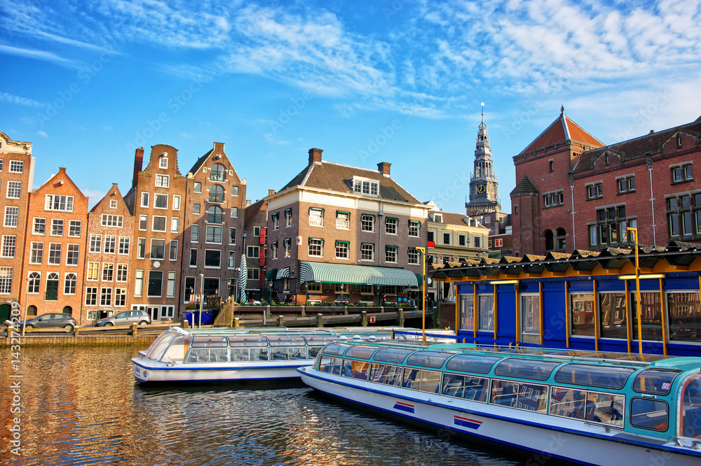 Naklejka premium Damrak Canal with boats and dancing houses in Amsterdam