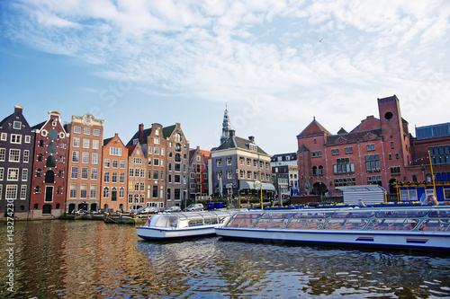 Damrak Canal with boats and dancing houses of Amsterdam