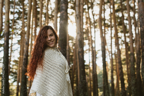 Horizontal outdoors shot of smiling female in the sunny woods looking at camera.