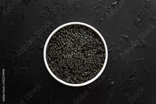 black caviar in white bowl on black background