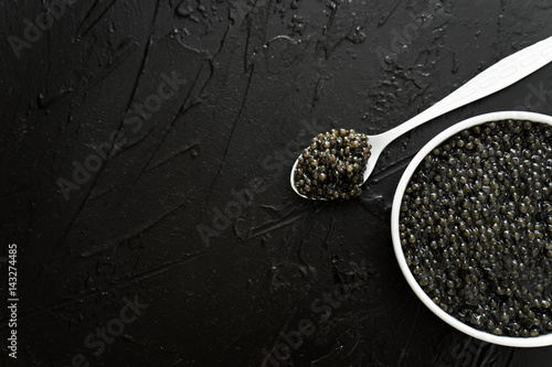 black caviar in white bowl  on black  background