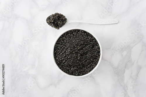 black caviar in bowl and on white shoop on marble  background