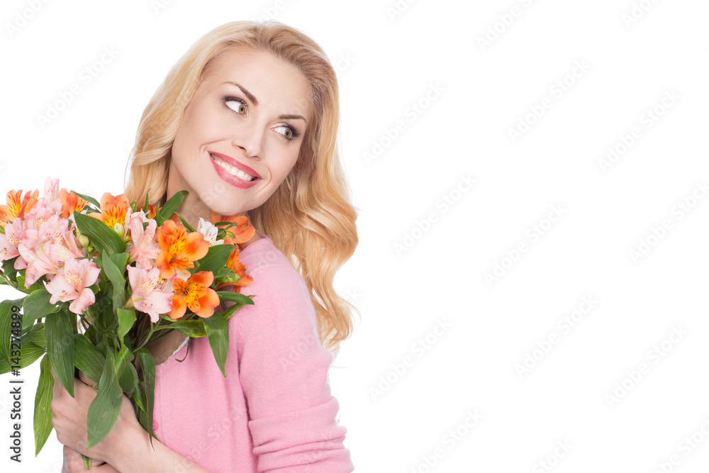 Joyful soul. Gorgeous cheerful mature woman holding bunch of flowers looking over the shoulder smiling happily isolated on white