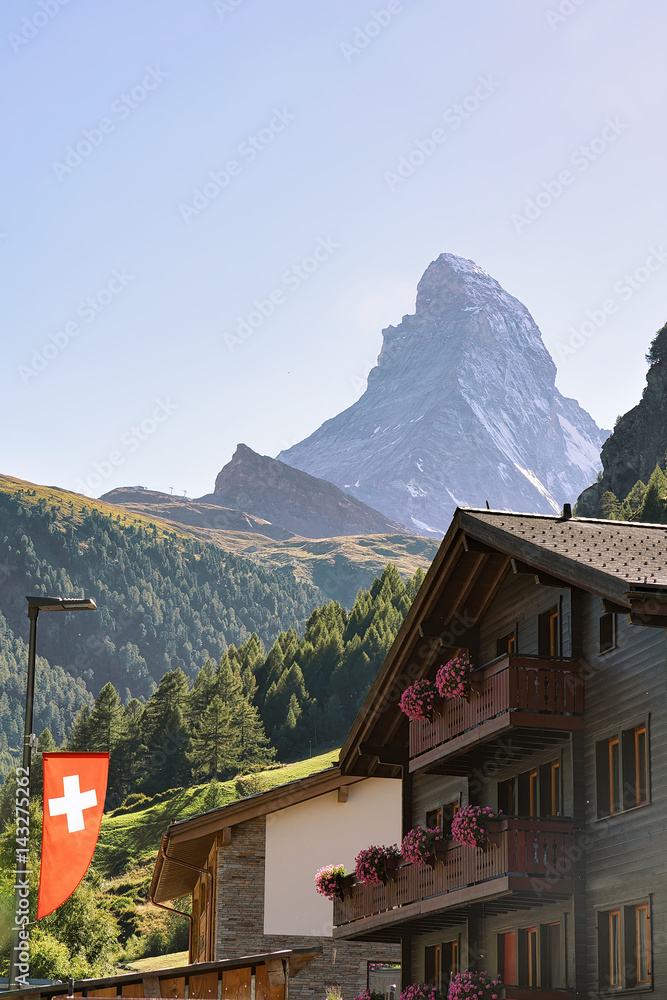 Traditional Chalet in Zermatt with Matterhorn peak with Swiss flag