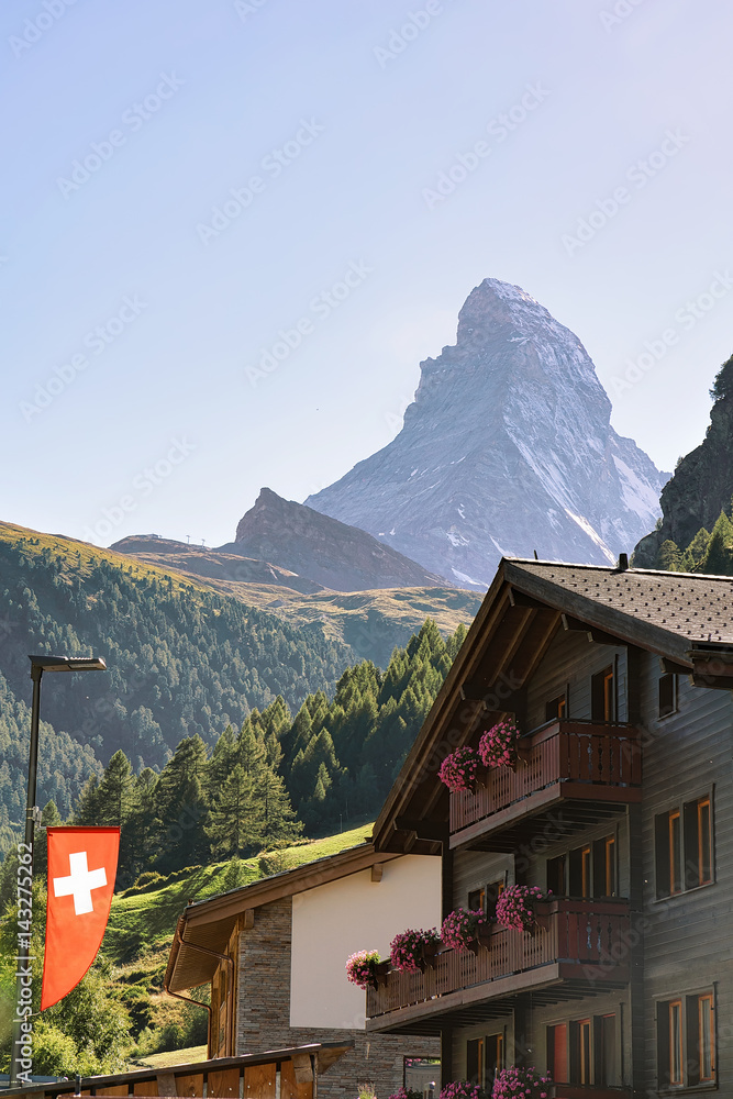 Obraz premium Traditional Chalet in Zermatt with Matterhorn peak with Swiss flag