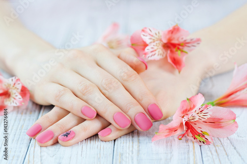 Woman hands with pink manicure on finger nails and delicate flowers
