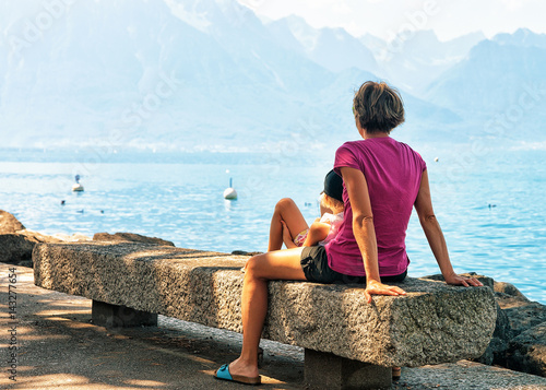 Mother and daughter sitting on bench at Geneva Lake Montreux
