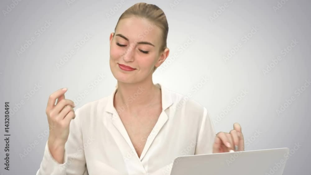Businesswoman in a good mood dance, sitting on the desk with laptop, and answer a phone call on white background. Businesswoman in a good mood dance, sitting on the desk with laptop, and answer a phone call on white background.