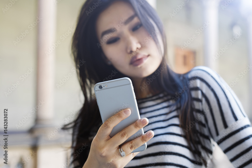 Student girl wearing casual clothes it chatting with friends by a smartphone. Photo of the beautiful model look asian woman surfing the web by a mobile phone connected to the wi-fi.