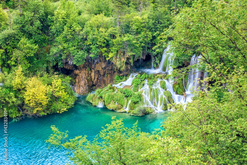 Waterfall in the green summer forest with turquoise water of the lake at Plitvice National park  Croatia. Nature background suitable for wallpaper  cover or guide book