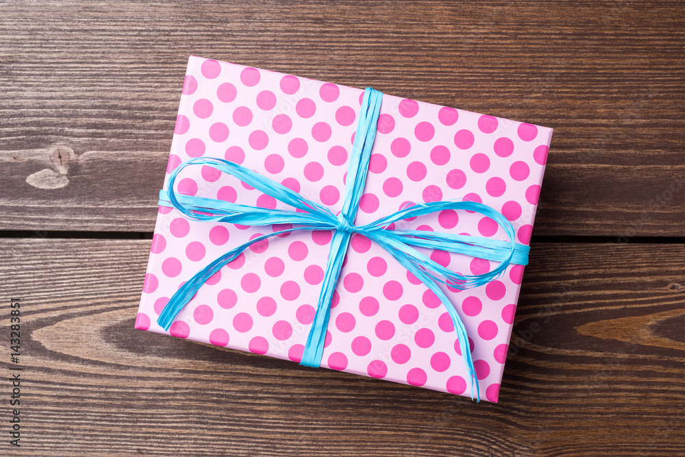 Pink dotted gift box on wooden table Pink dotted gift box on wooden table