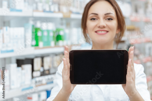 Your order is ready. Selective focus on a digital tablet with the copyspace on in hands of a cheerful pharmacist at the local drugstore.