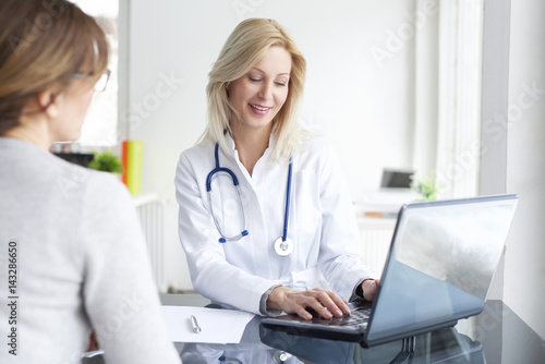 Consulting in the hospital. Shot of a middle aged female doctor sitting in front of laptop and consulting with her patient.