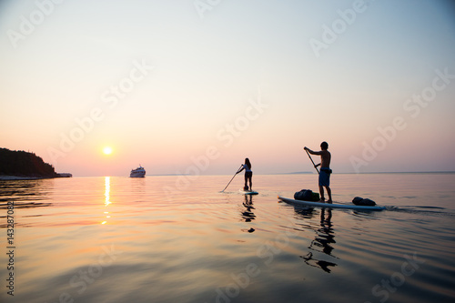 Obraz na płótnie Attractive Young couple Stand Up Paddle Boarding, w salonie