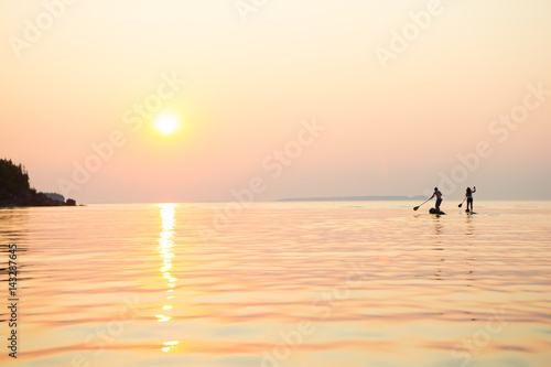 Attractive Young couple Stand Up Paddle Boarding, © Colin