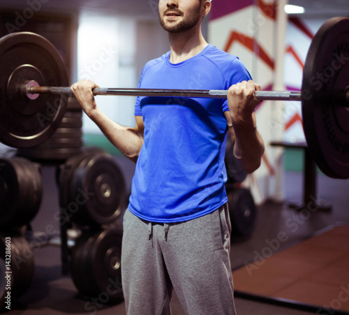 Strong man lifting barbell as a part of crossfit exercise routine.