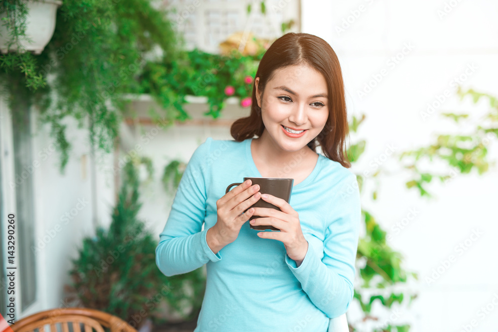 Portrait of a happy asian woman thinking and holding coffee or tea cup at breakfast Portrait of a happy asian woman thinking and holding coffee or tea cup at breakfast