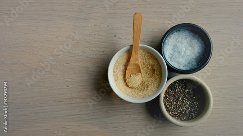 salt, pepper and sugar seasoning in round ceramic saucer on wooden table