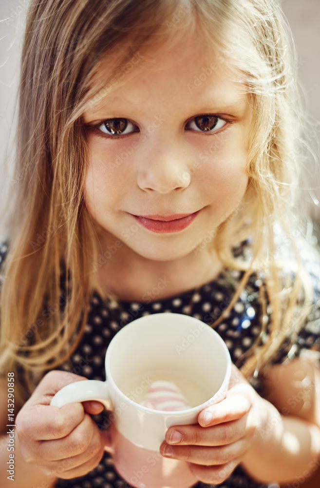 Cute girl holding cup with milk and marshmallow. Childhood concept. Cute girl holding cup with milk and marshmallow. Childhood concept.