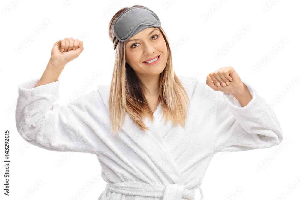 Young woman wearing bathrobe and sleeping mask stretching herself Young woman wearing bathrobe and sleeping mask stretching herself