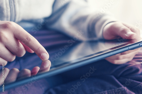 Closeup of a boy looking for information on a tablet (high key)