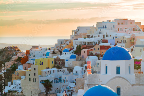 vew of Oia, traditional greek village of Santorini, with blue domes of churches in pink sunset light, Greece