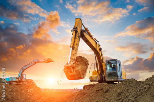 Tableau sur toile excavator in construction site on sunset sky background