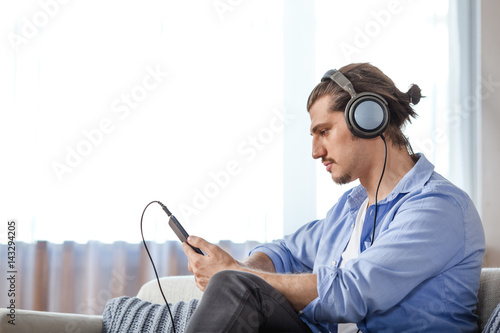 Handsome guy listening to music on internet with tablet photo