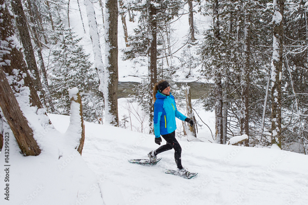 Lone woman running in the forest on snowshoes