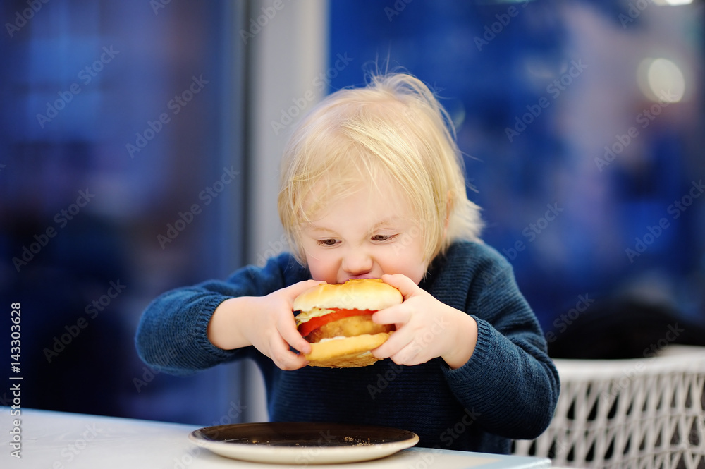 Cute blonde boy eat hamburger at fast food restaurant Cute blonde boy eat hamburger at fast food restaurant