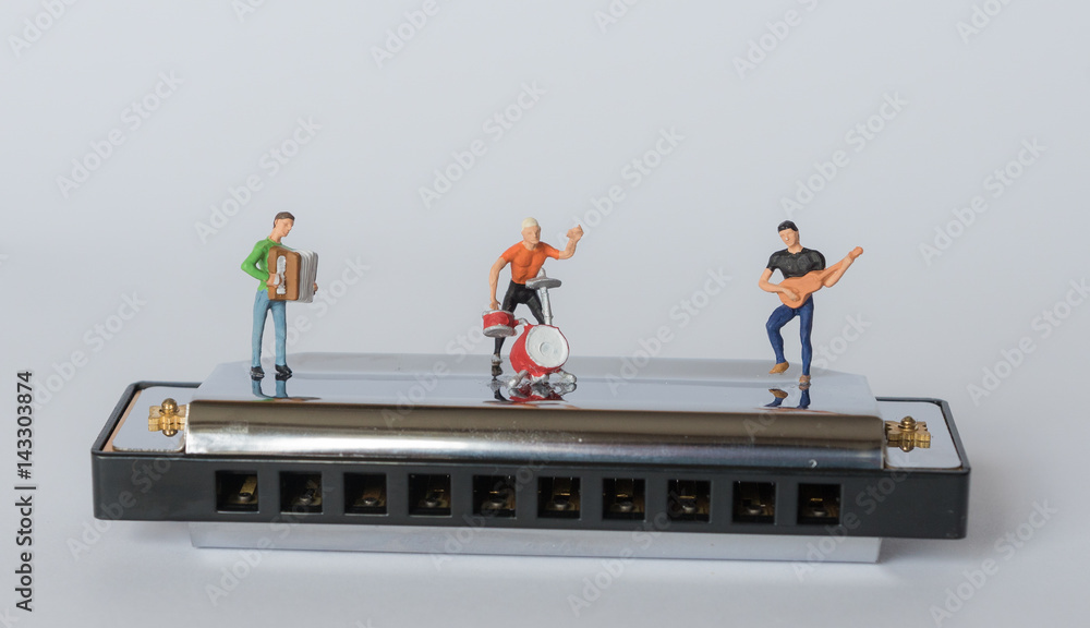 Miniaturband spielt auf einer Mundharmonika