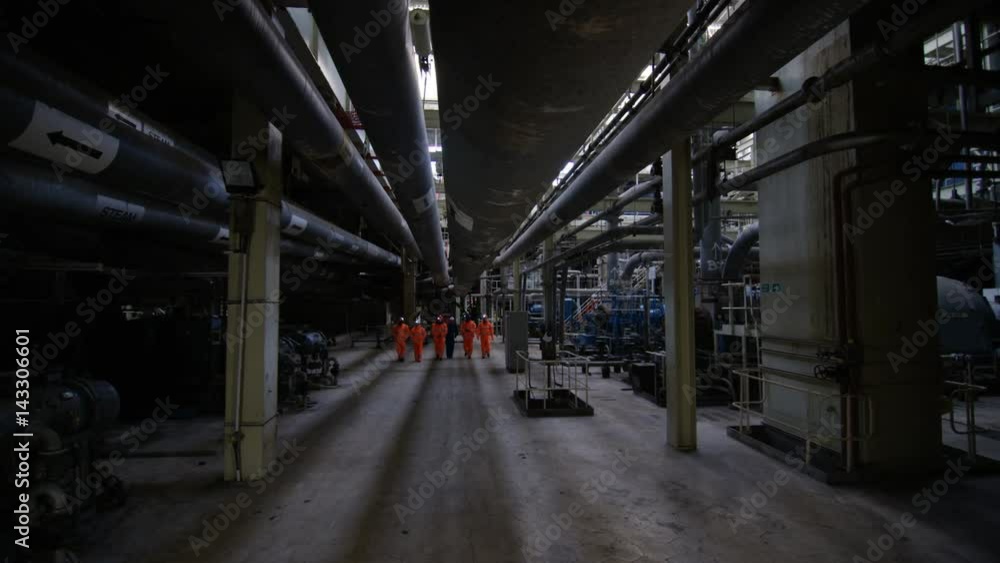 Team of engineers in power station, wide shot of workers & interior structure Team of engineers in power station, wide shot of workers & interior structure