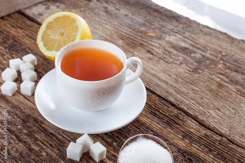 sweet cup of fruit tea with lemon and sugar on a wooden background