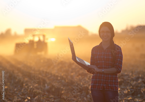 Woman with laptop in front of tractor