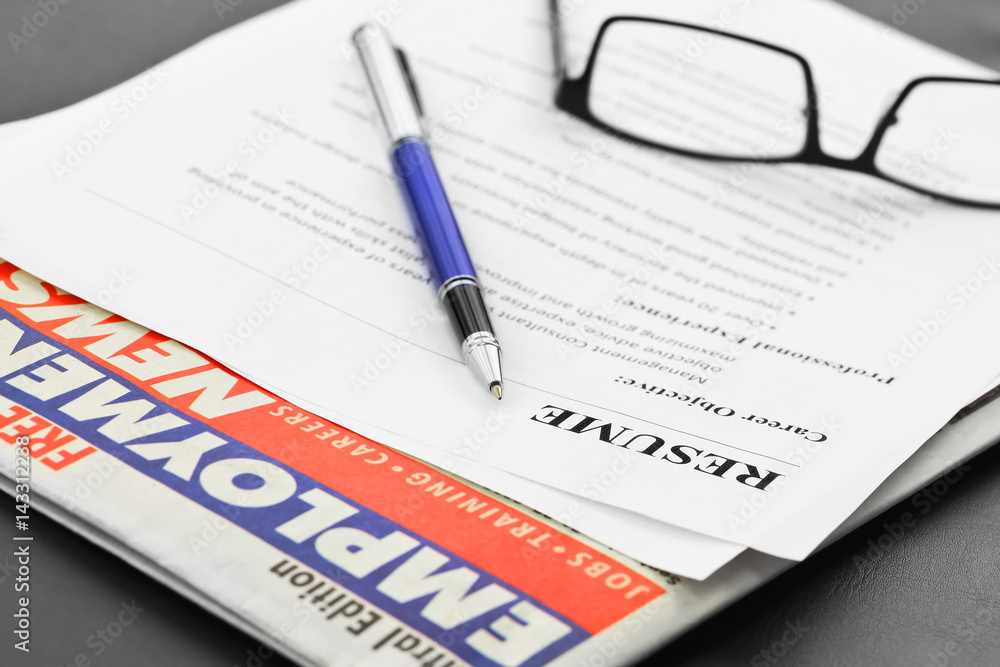 Closeup of resume with pen and glasses on the table with newspaper Closeup of resume with pen and glasses on the table with newspaper